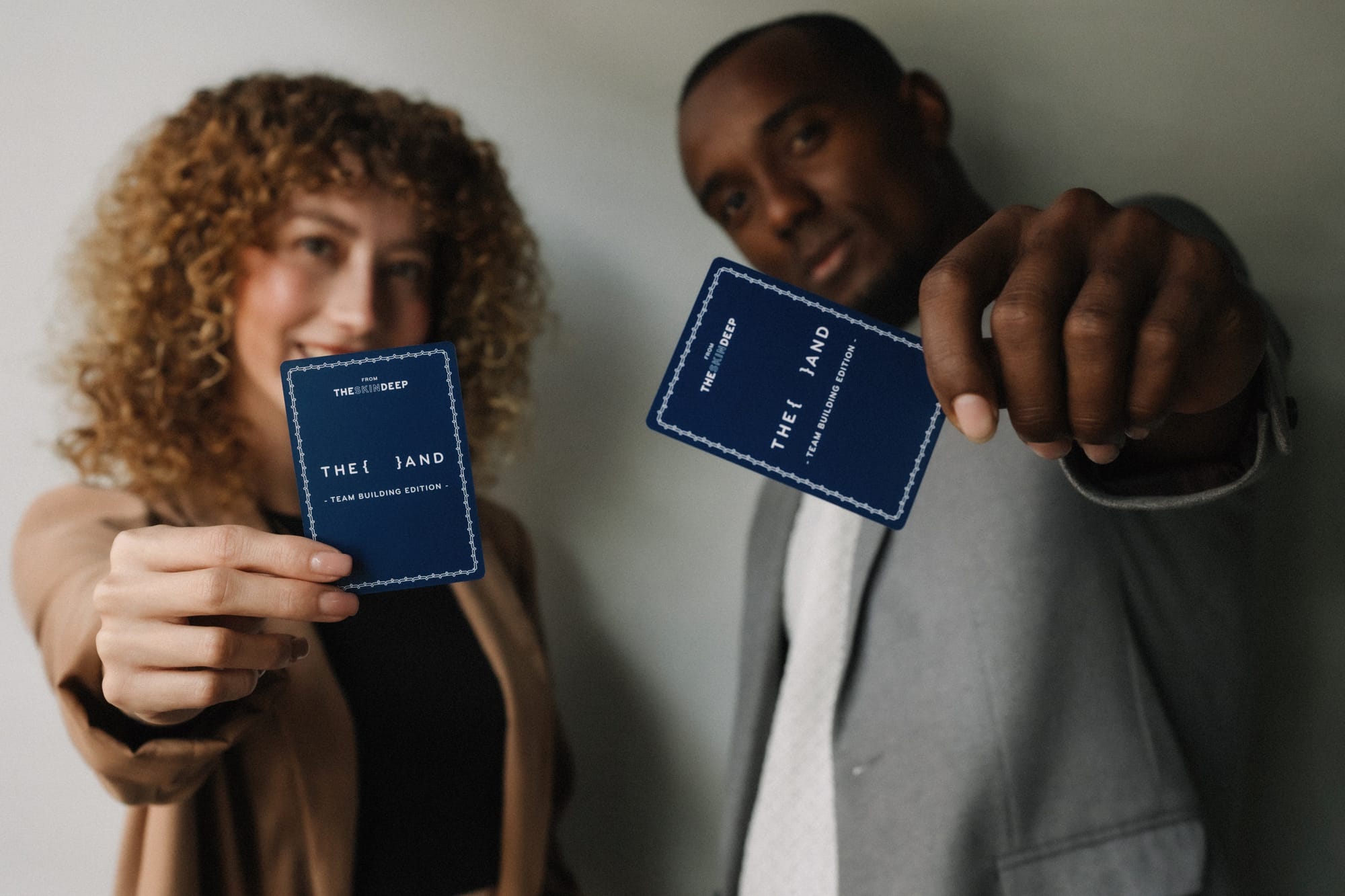 Two coworkers holding {THE AND} Team Building Edition Cards