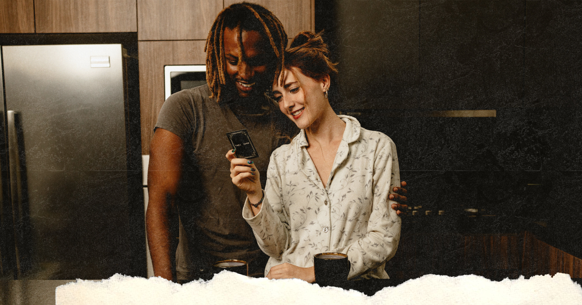 Picture of a couple in the kitchen drinking coffee, eating cookies playing a card game and smiling