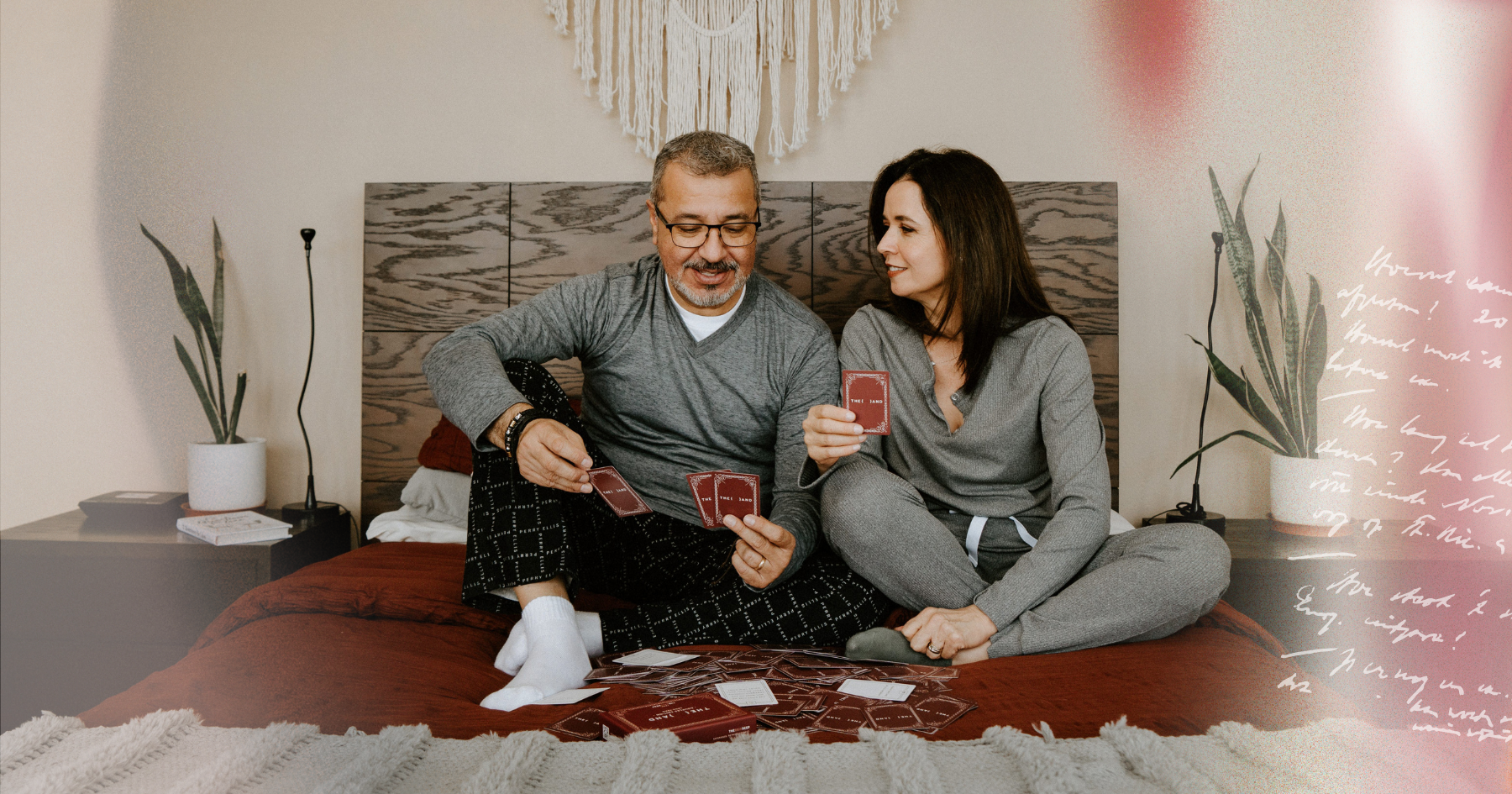 Picture of a couple sitting in bed, playing a card game and laughing together