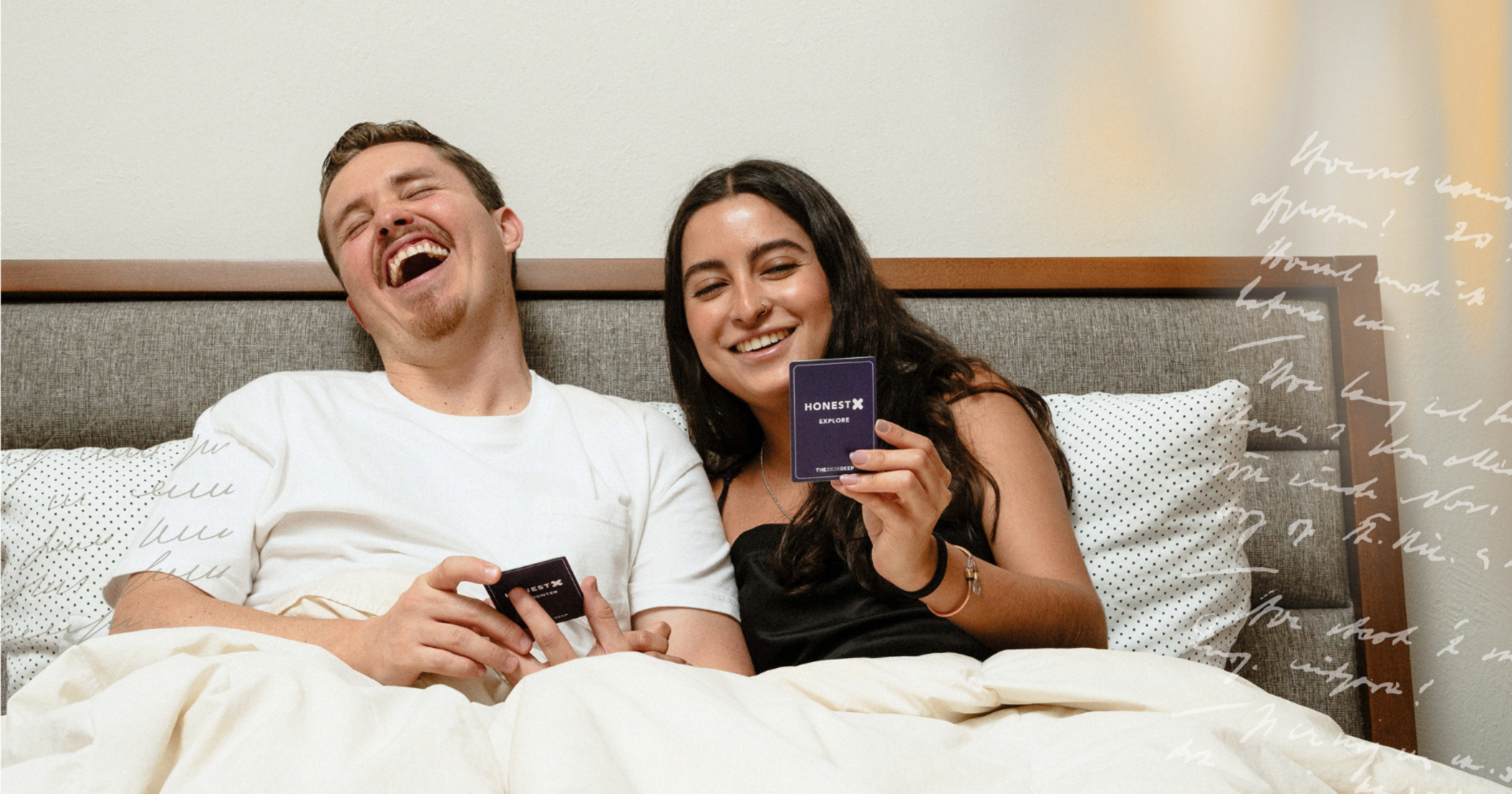 Picture of a couple playing a card game in bed laughing
