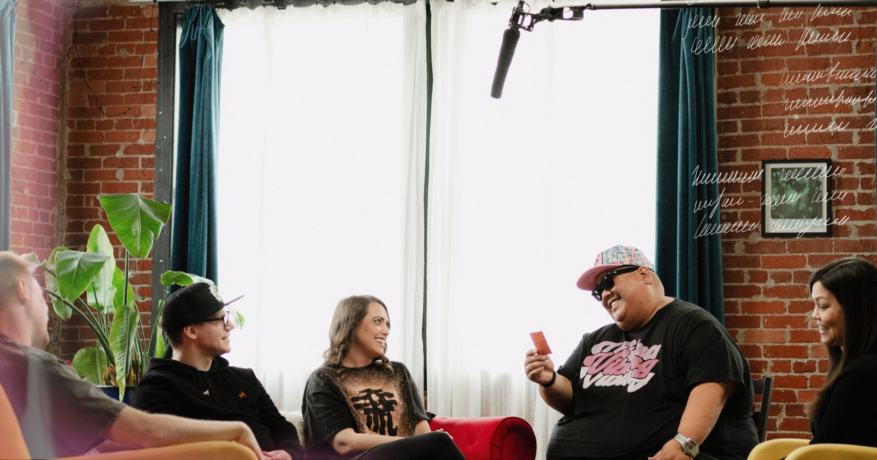 Picture of a group of 5 friends sitting down on yellow couches and laughing