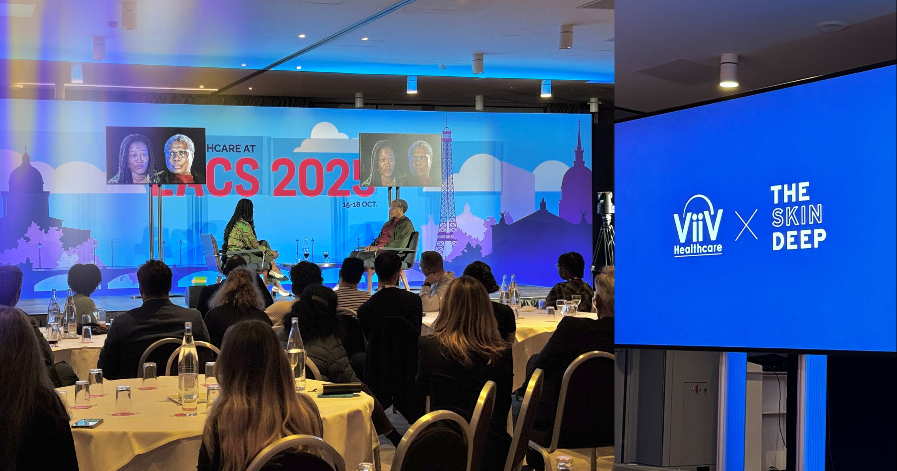 Picture of a room full of people and a stage with two people sitting face to face