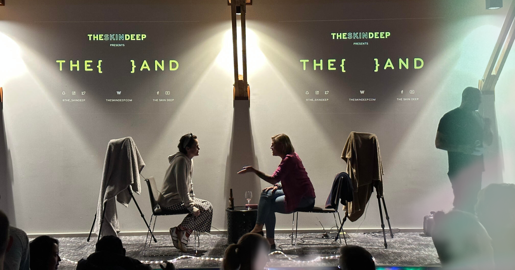 Picture of a room full of people and two people sitting facing each other on stage
