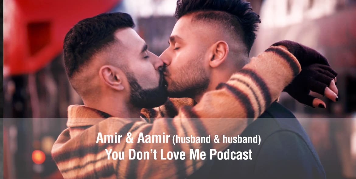 Picture of a South Asian Queer couple wearing coats and kissing on the street