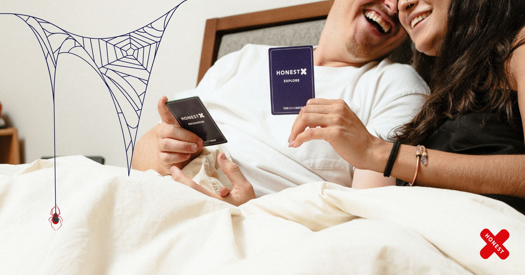 Picture of a couple laying in bed, under the sheets, laughing and playing Honest X relationship card game