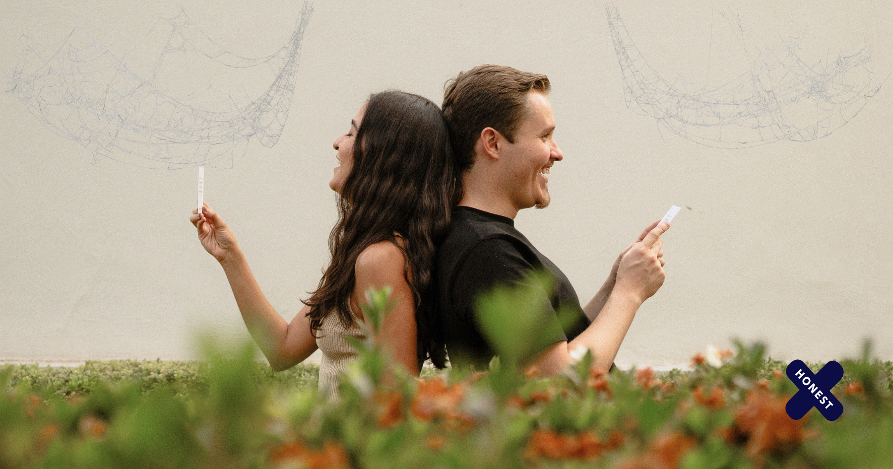 Picture of a couple back to back holding Honest X cards and smiling