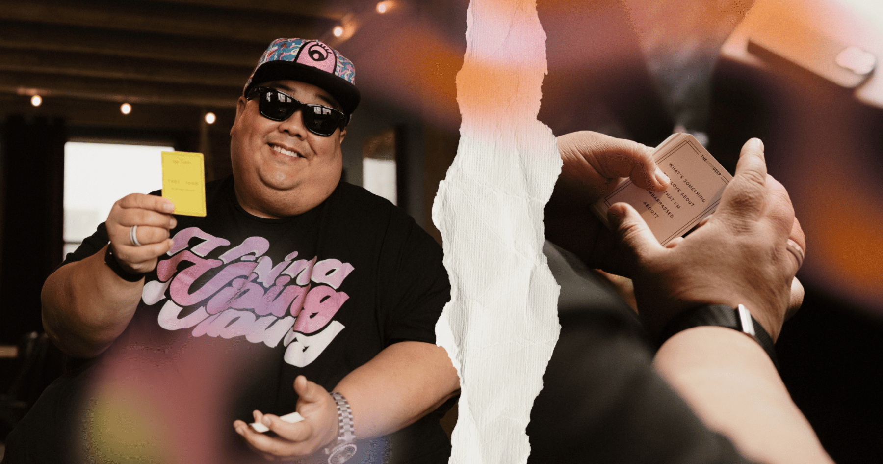 A man with a hat and sunglasses holding a bunch of cards and smiling