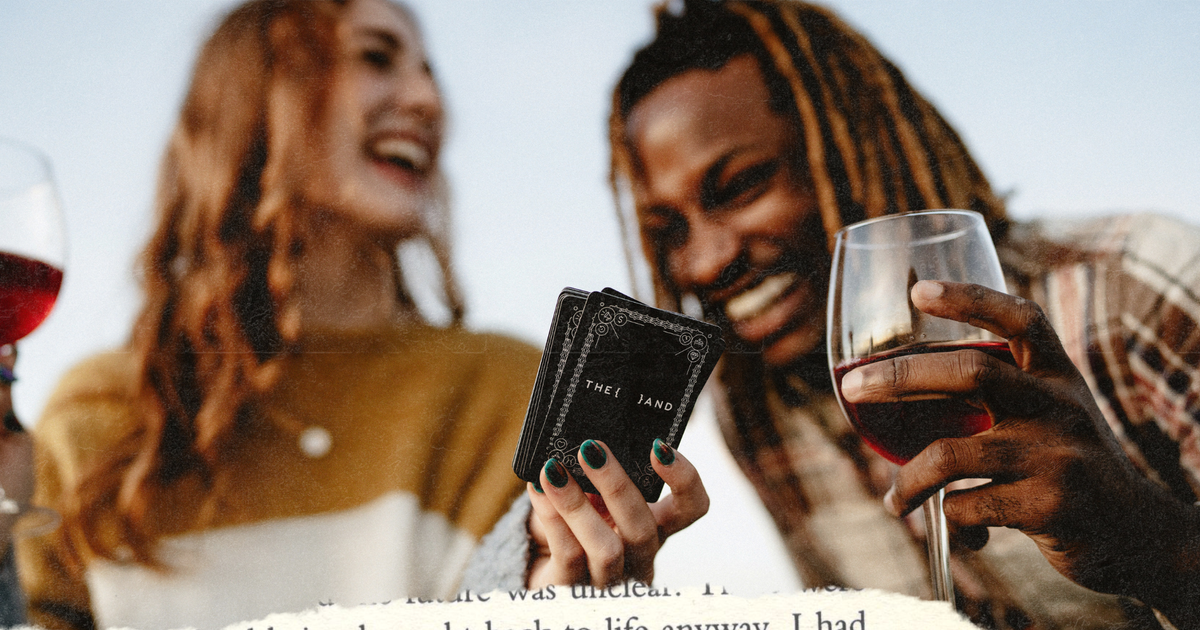 Picture of a couple drinking red wine and playing a card game while laughing together