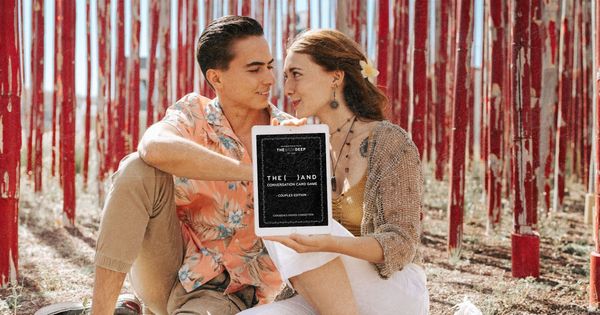 Picture of a couple in a romantic picnic date with an tablet and a digital conversation card game