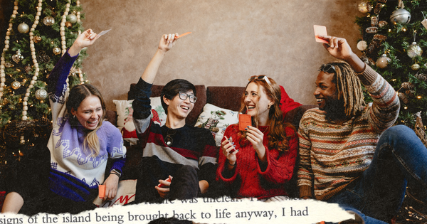 Picture of four friends sitting on a couch and playing a conversation card game raising their hands and laughing, with Christmas trees behind during holiday season