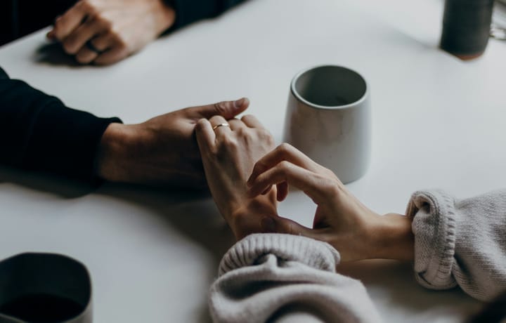 A couple sharing a coffee together with hands touching. 